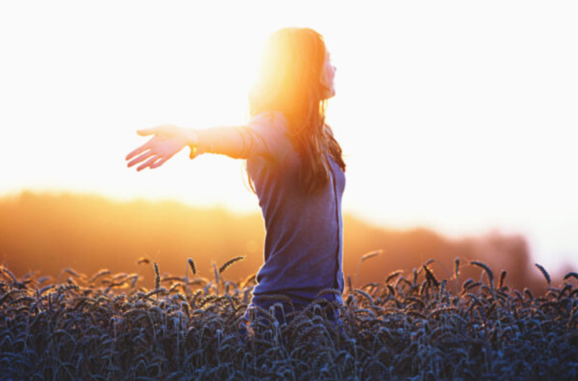 Young woman enjoying nature and sunlight in straw field